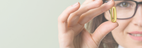 woman with glasses holding an immunity gel cap dietary supplement