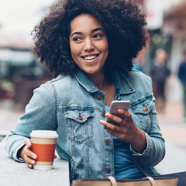 Woman holding onto phone with to-go coffee