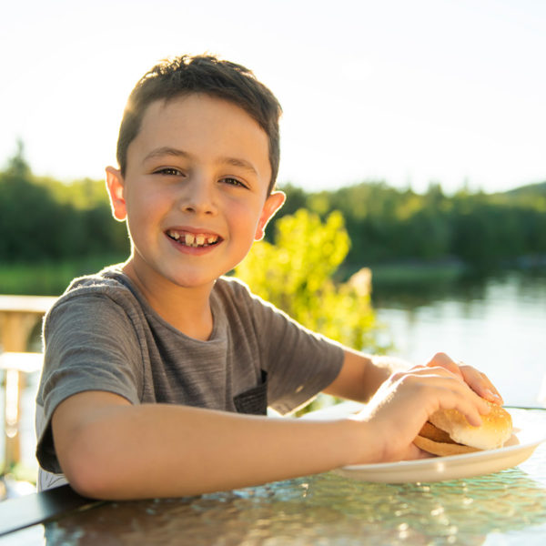 Boy eating hamburger outside