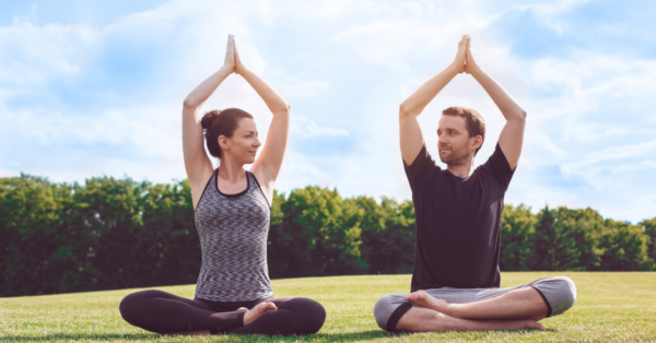 two people practicing yoga outside